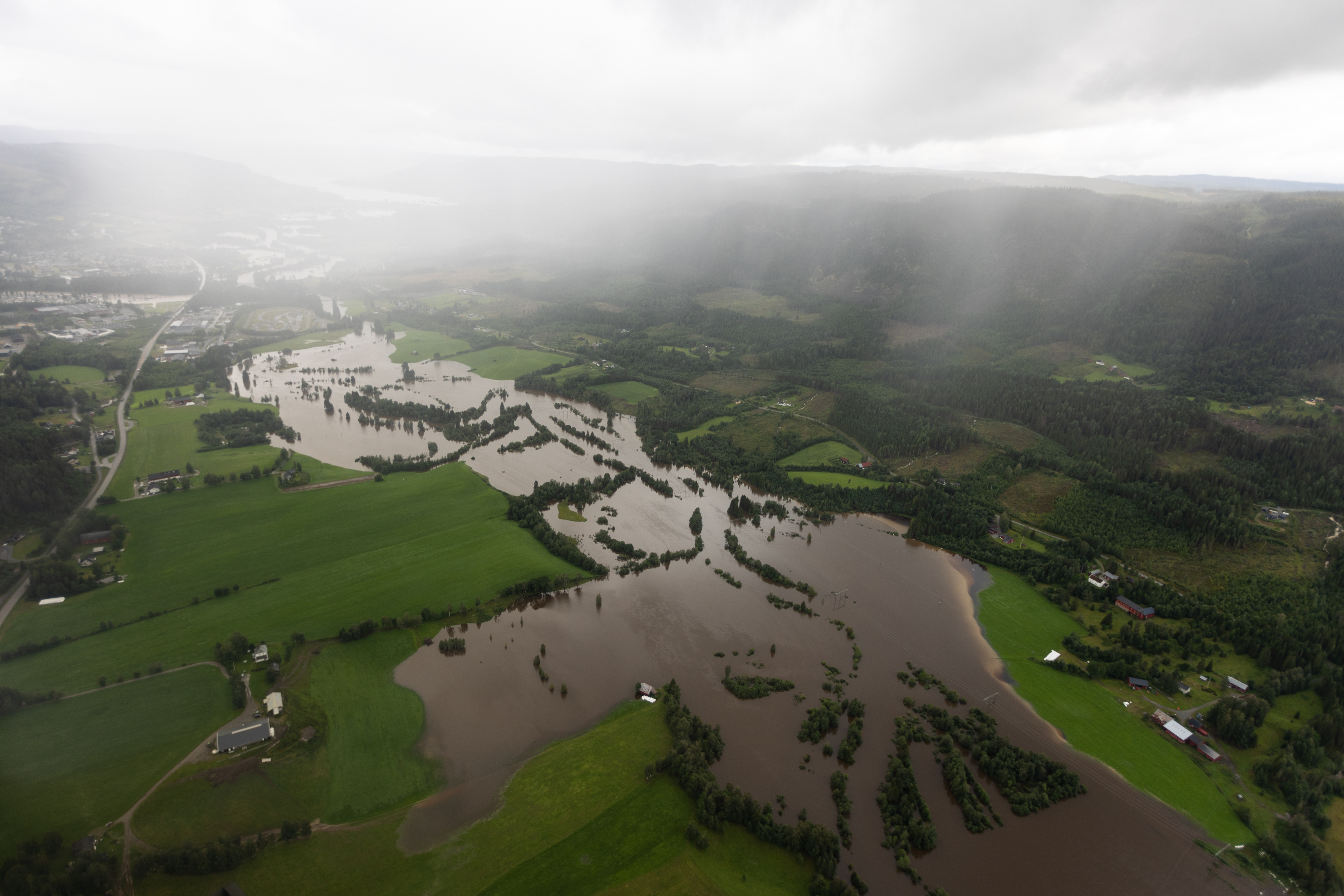 brun elv som har gått over sine bredder, oversvømte grønne jorder 