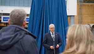 Havforskningsdirektøren holder tale foran blått teppe som dekker bautaen før avduking.