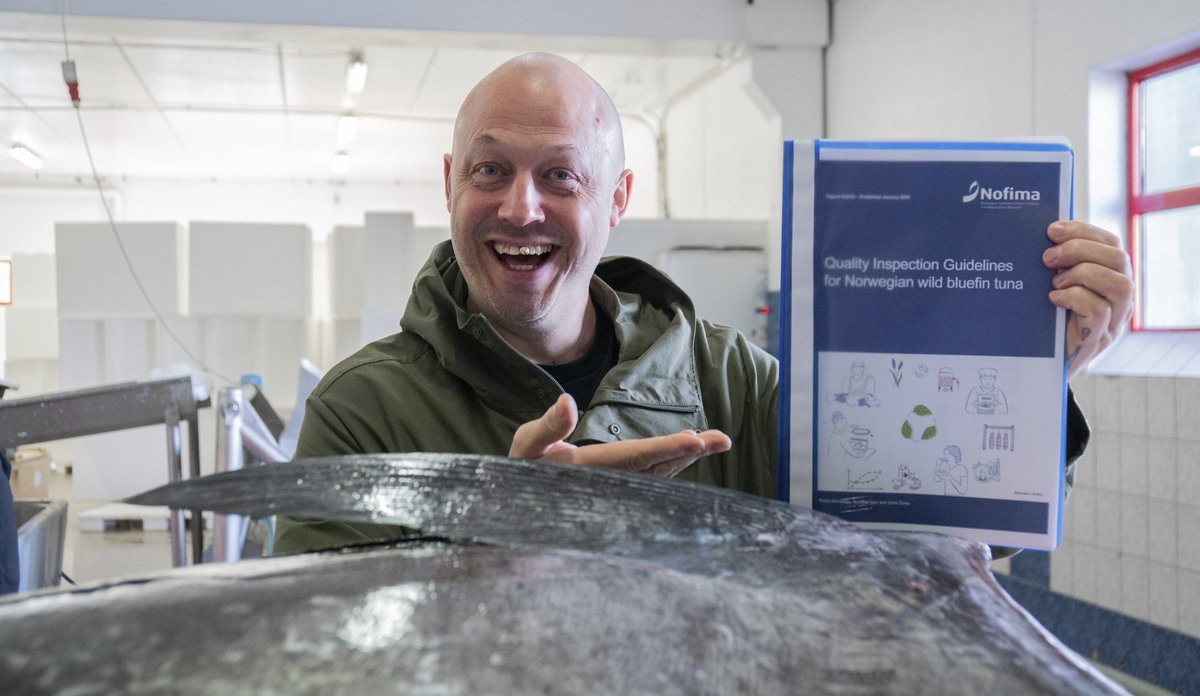 foto av mann bak gigantfisk med plastmappe han viser til kamera