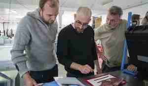 Foto av tre menn som studerer kotelett og manual