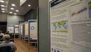 Ei rekke vitskapelege postarar er hengde opp på mellombelse veggar, langs kantane av konferansesalen