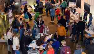 Folk flokker seg rundt haien som ligger utstilt på et bord inne på Polaria før disseksjonen tok sted ute. 