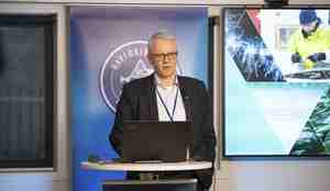 En mann står bak et podie med en datamaskin. I bakgrunnen ser man Havforskningsinstituttet sin logo og framsiden på årets risikorapport.