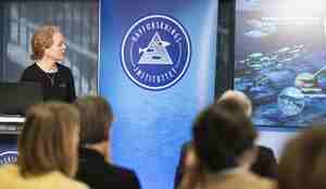 En kvinne holder et foredrag foran en folkemengde. 