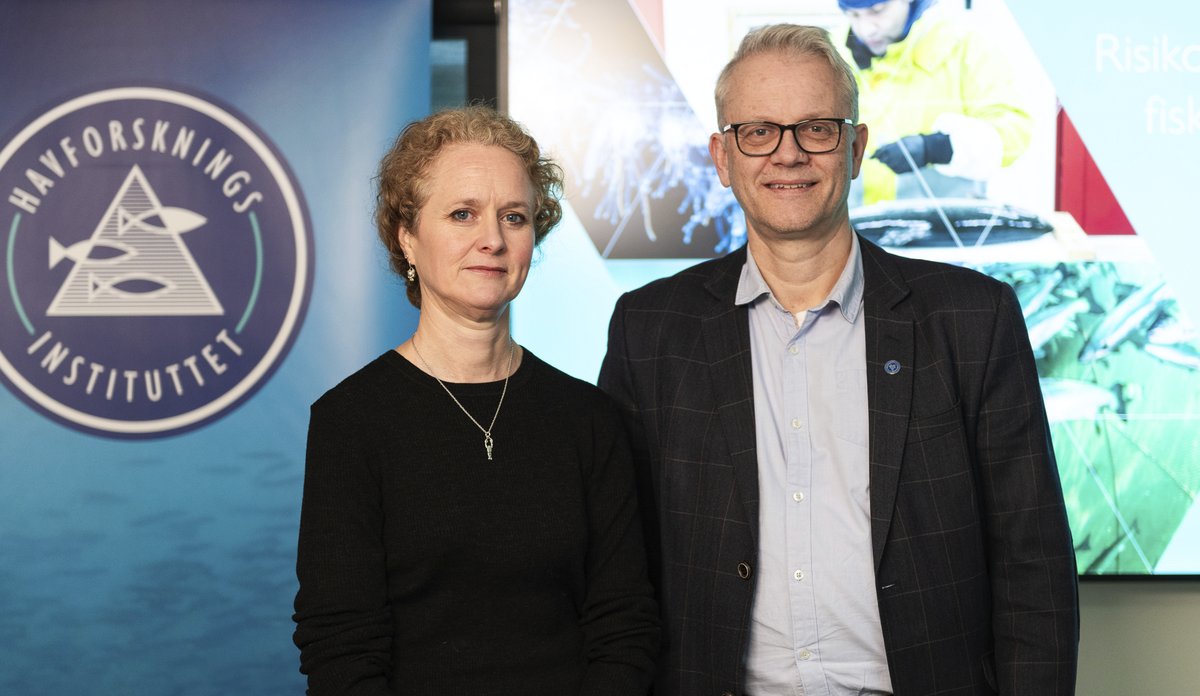 en mann og en kvinne foran et banner med logo 