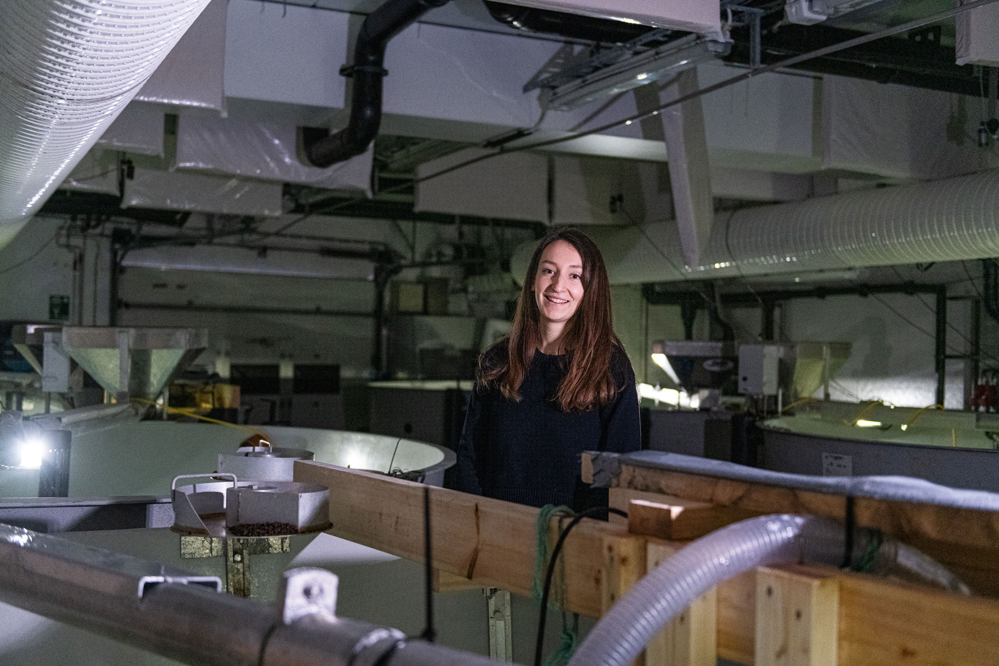 Bilde av en person blant fiskekar, vanslanger og rør.