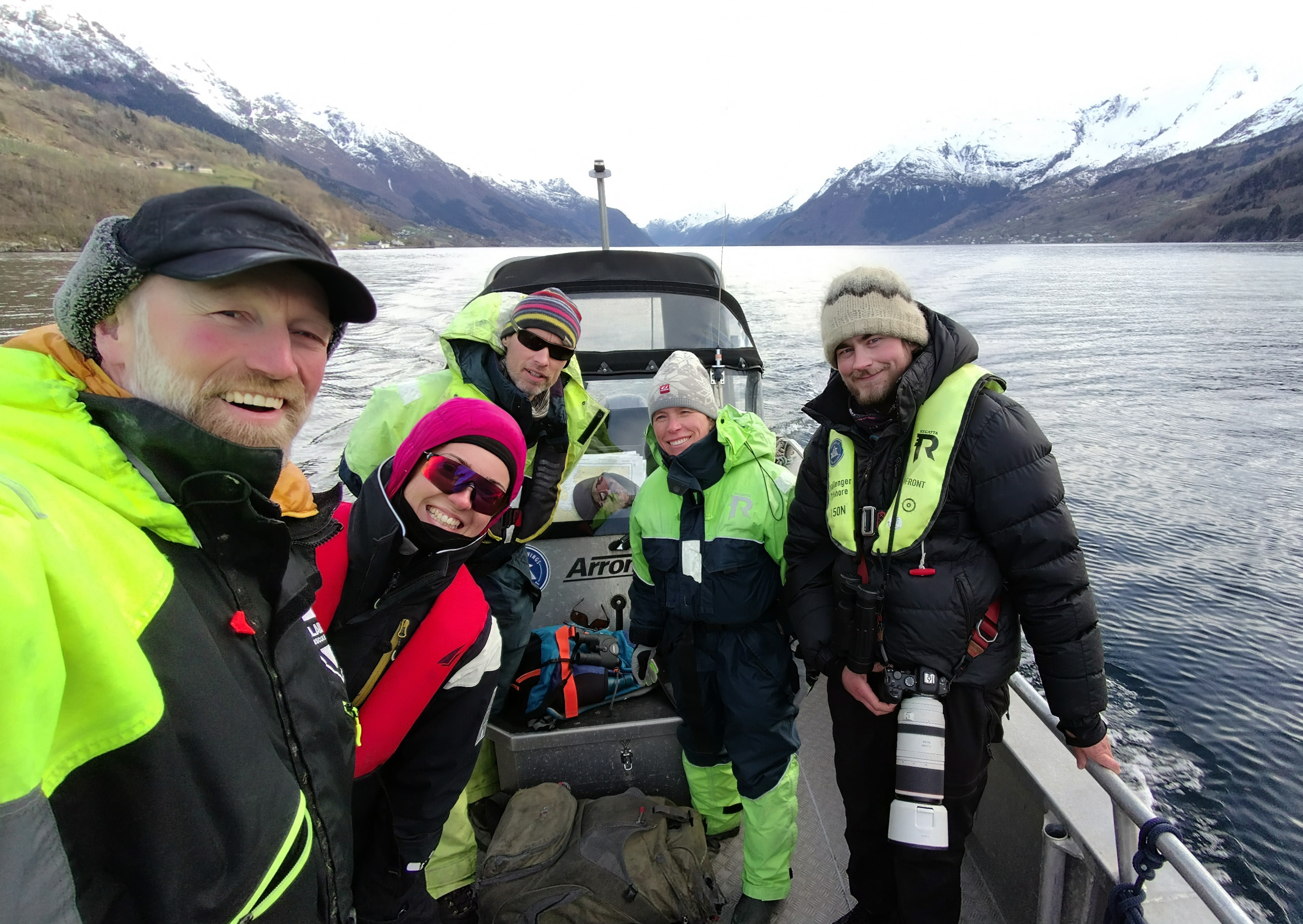 Fem personer står i en småbåt