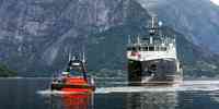 

En oransje ubemannet farkost og et forskningsfartøy i vannet med fjell i bakgrunnen.