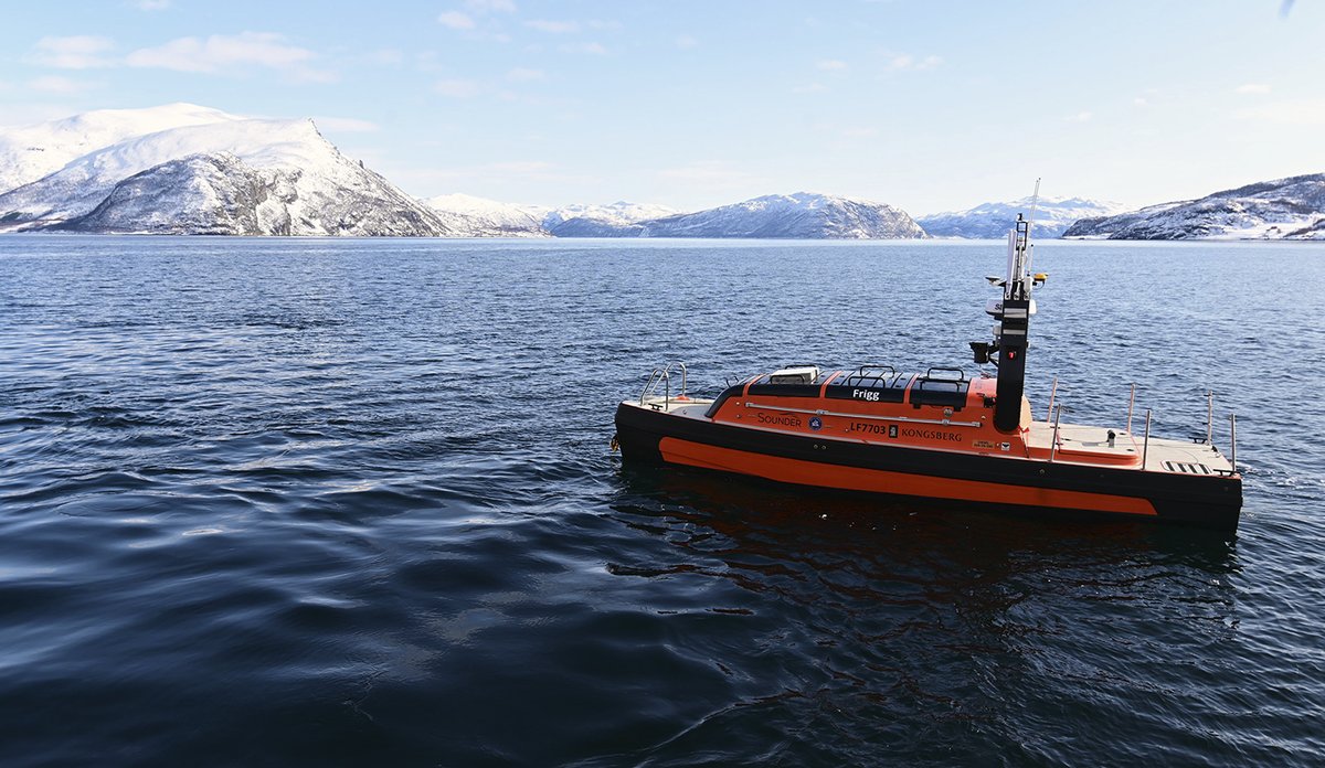 
Ubemannet farkost Frigg ligger på blått hav i nordnorsk fjord. Fjell i bakgrunnen og pent vær.
