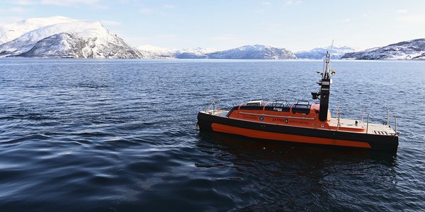 

Ubemannet farkost Frigg ligger på blått hav i nordnorsk fjord. Fjell i bakgrunnen og pent vær.