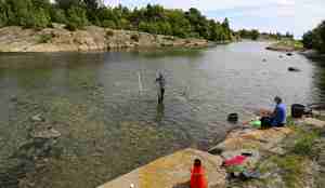 Mann og kvinne ved en elv. Kvinne holder opp et apparat.