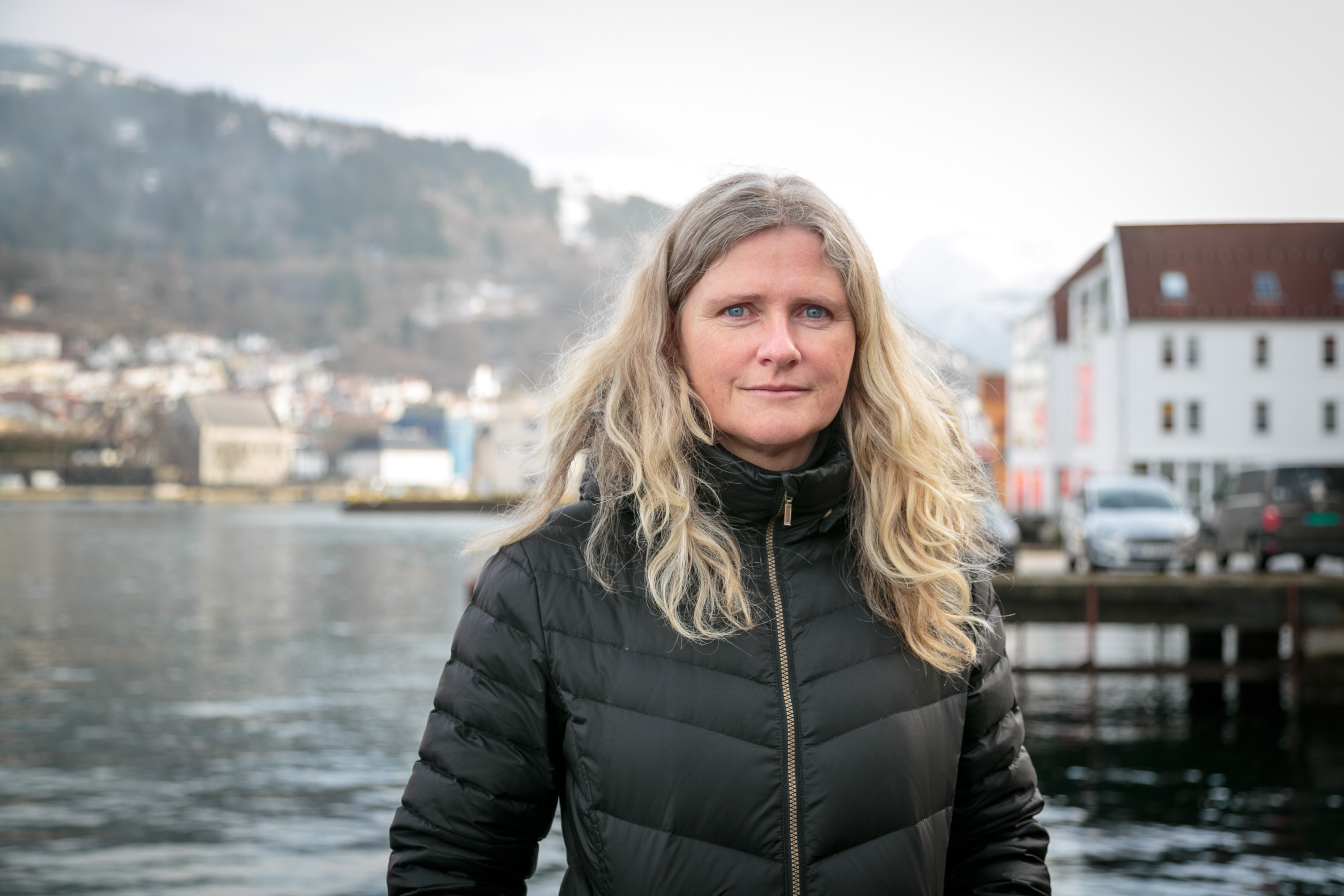 kvinne på kai ser i kamera 