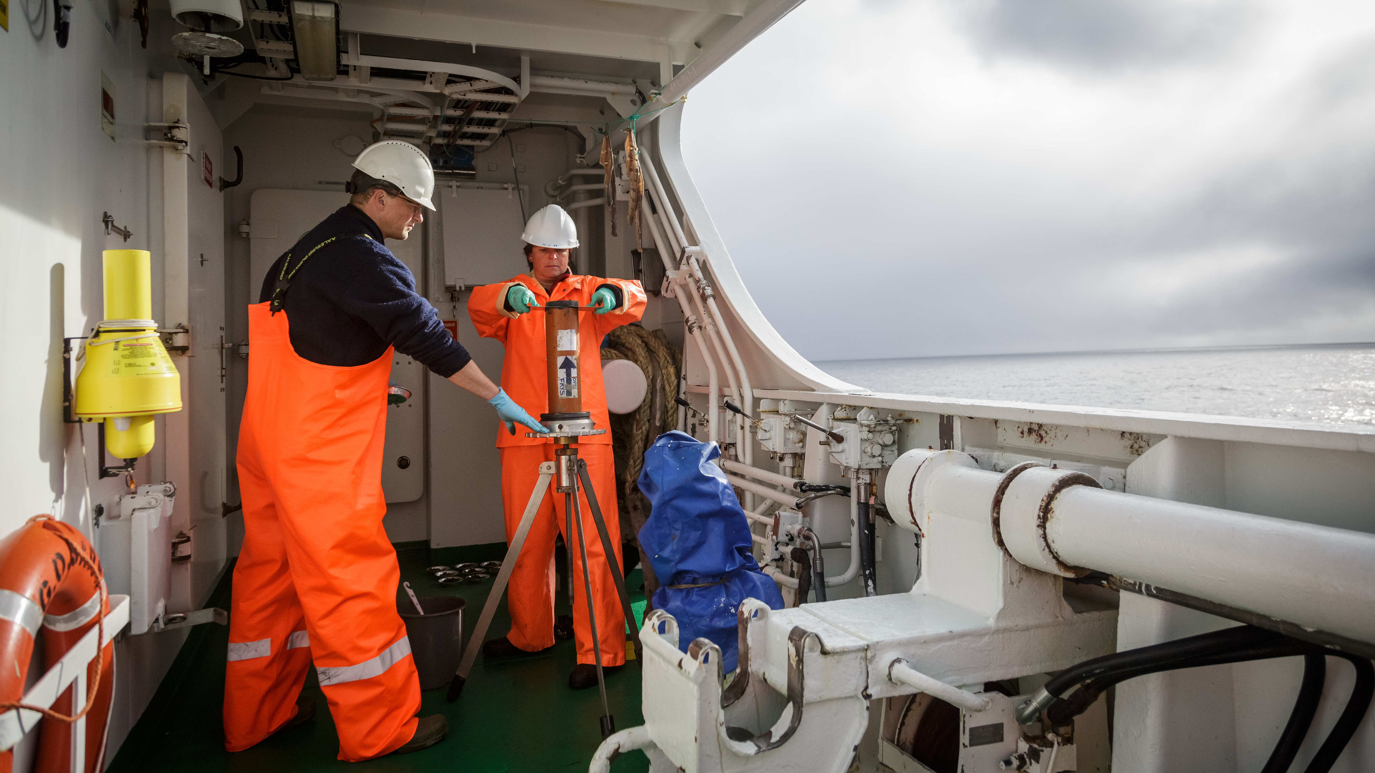 to personer jobber på dekk med havbunnsprøver