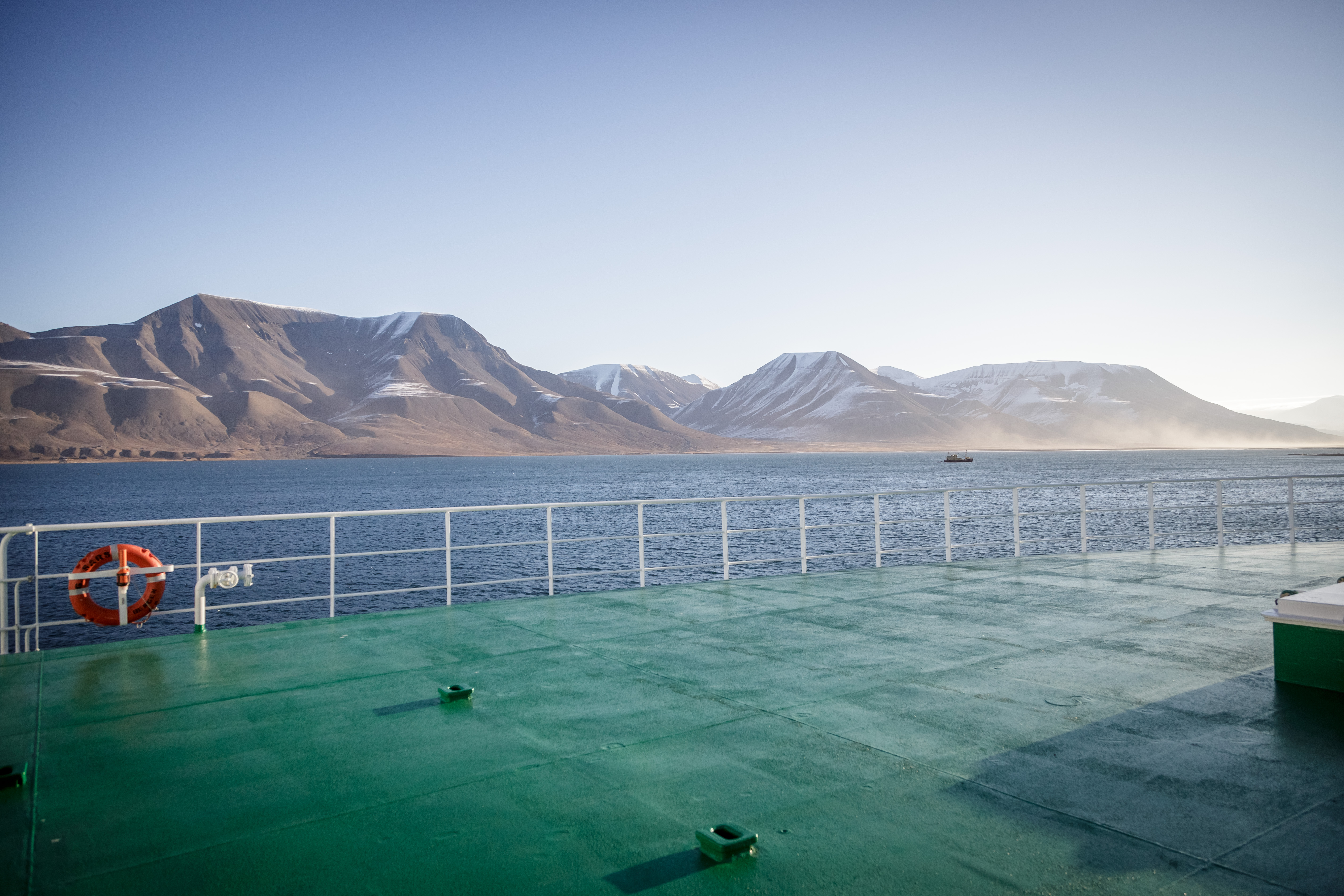 bratte nakne fjell og blått hav bak båtripe 