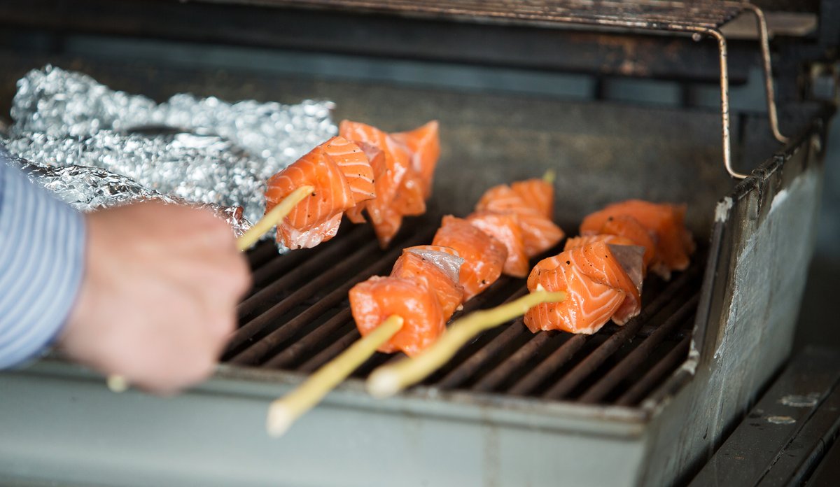
Grillspyd med laks blir lagt på grillen.