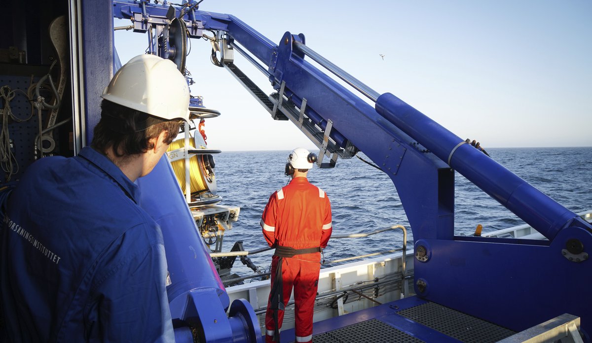 
To personer på båt som ser på en maskin