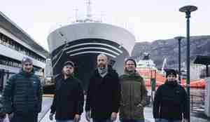 bilde av fem menn som står oppstilt foran baugen på et skip