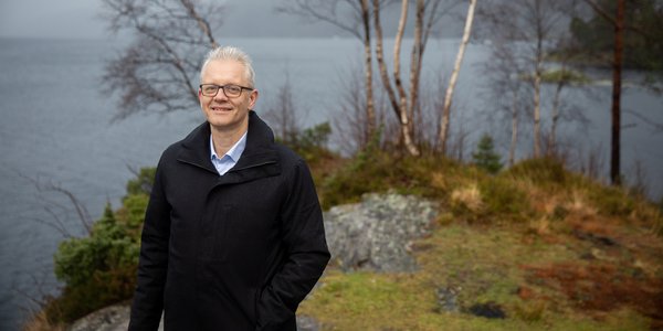 

mann stående på berg med sjø i bakgrunnen