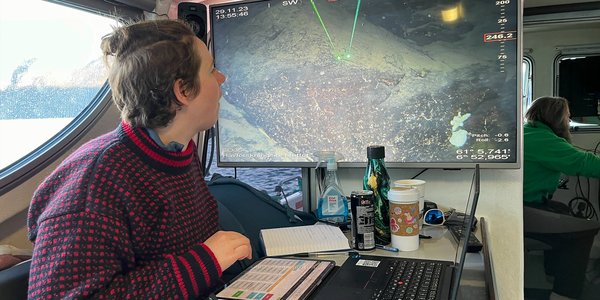 

En kvinnelig forsker sitter i styrehuset på en båt og ser på en skjerm