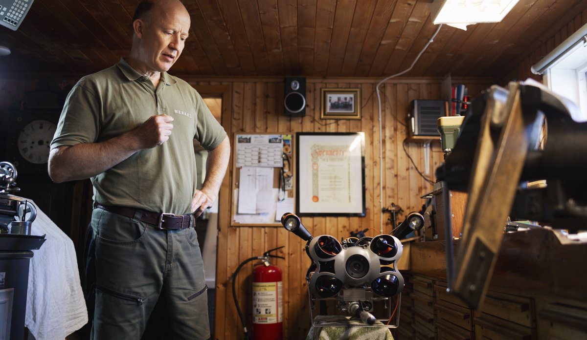 foto av mann på verksted med en slags robot på et bord