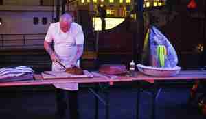 mann bak bord med stort fiskehode