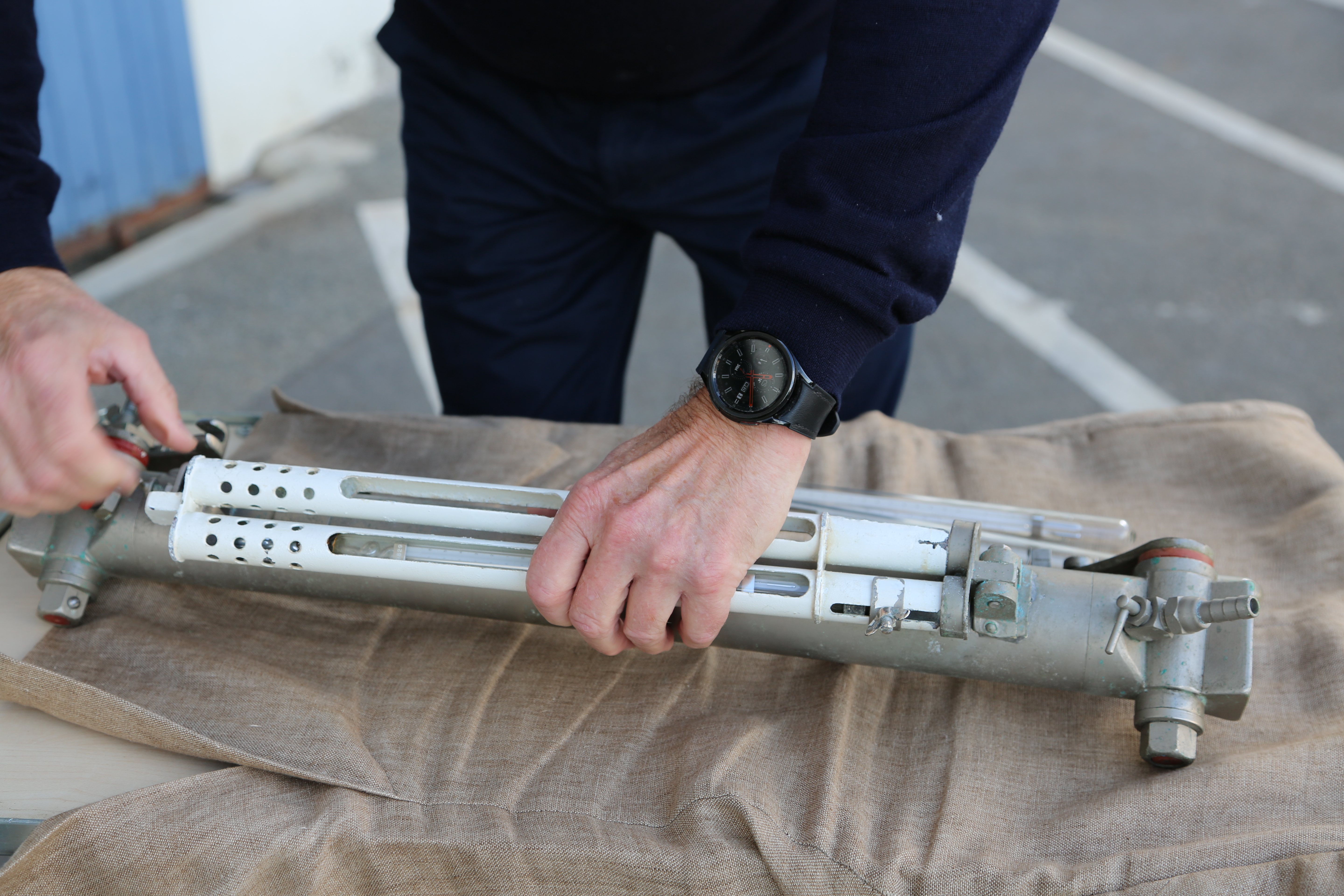 Nærbilde av termometer plassert i metallhylse og montert på vannhenter