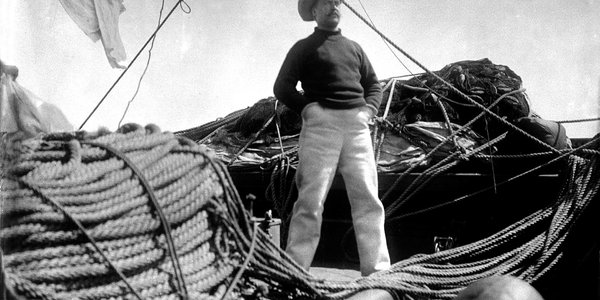 

Svarthvittbilde av Johan Hjort med hatt på dekk av forskningsfartøyet MIchael Sars. Vi ser trosser og taukveiler.