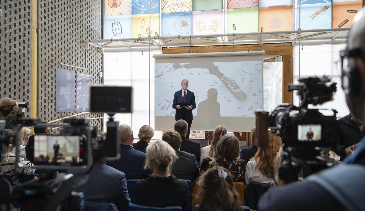 
En mann står på en scene framfor en fullsatt sal