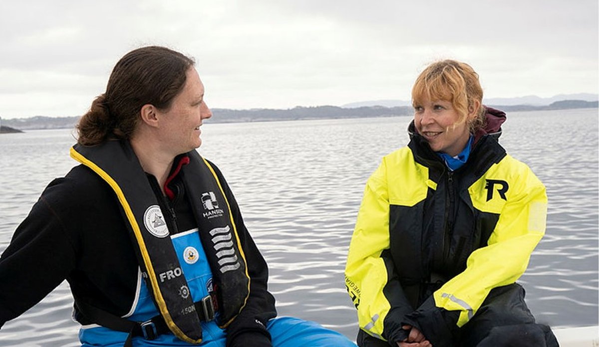 
Foto av to havforskere som prater med hverandre i en båt.