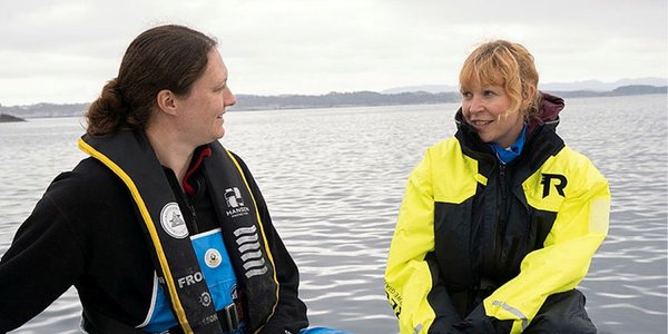 

Foto av to havforskere som prater med hverandre i en båt.