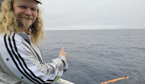 foto av mann foran sjø med oransje robot bak