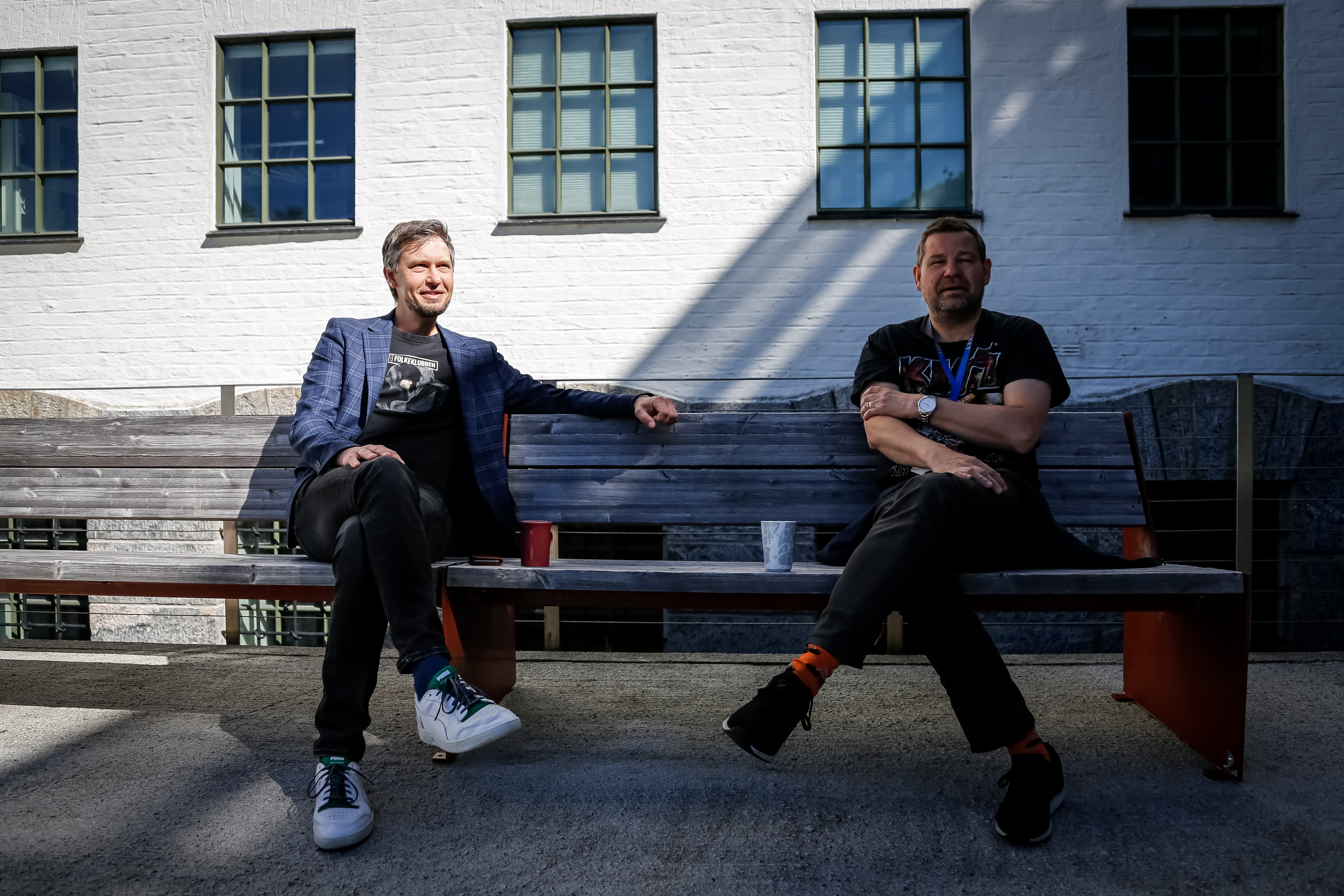 to menn smilende på en benk ute i solen