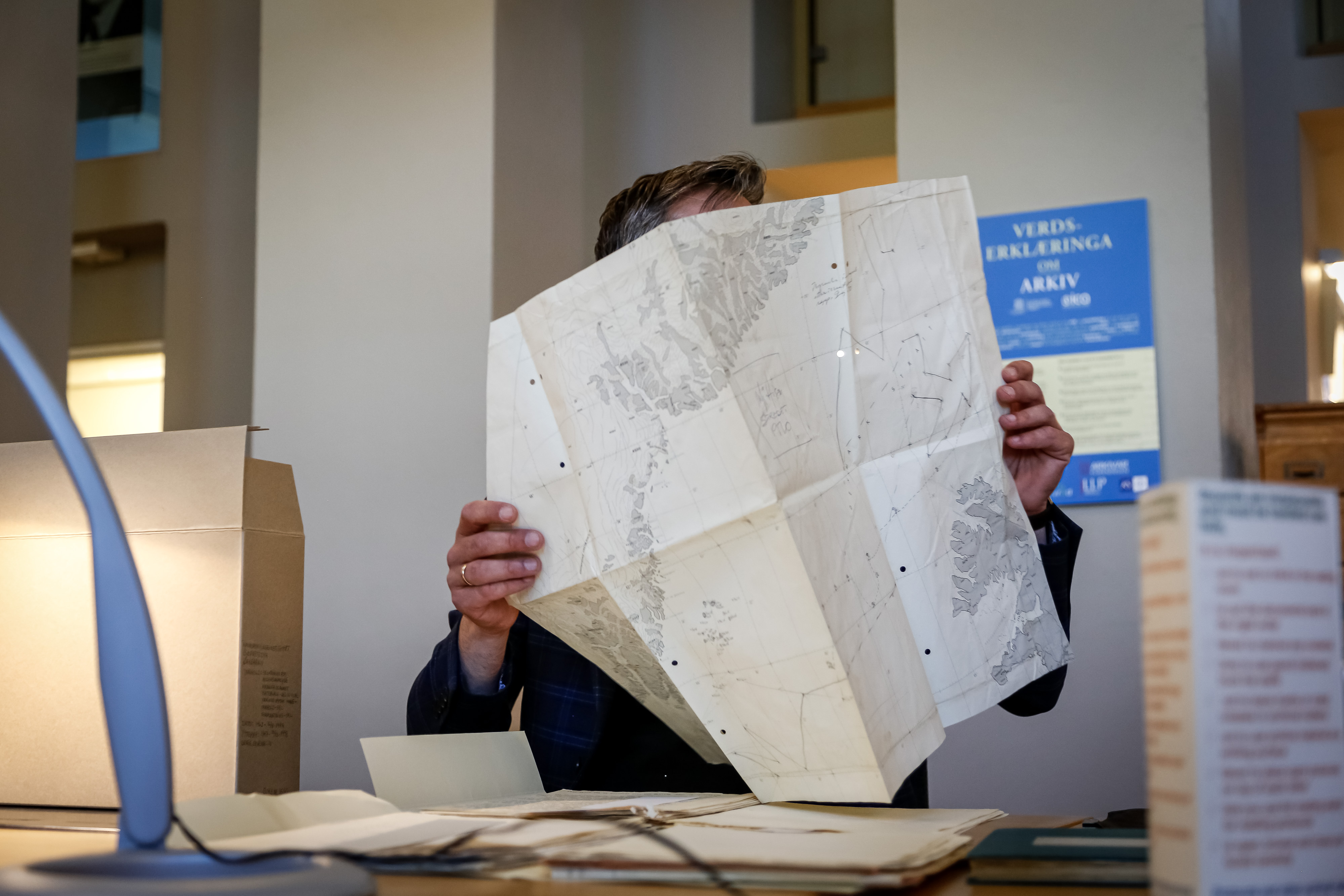 mann holder et eldre kart foran ansiktet 