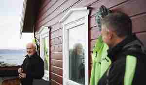 Foto av to menn som diskuterer noe på en terasse, hytte ved sjøen