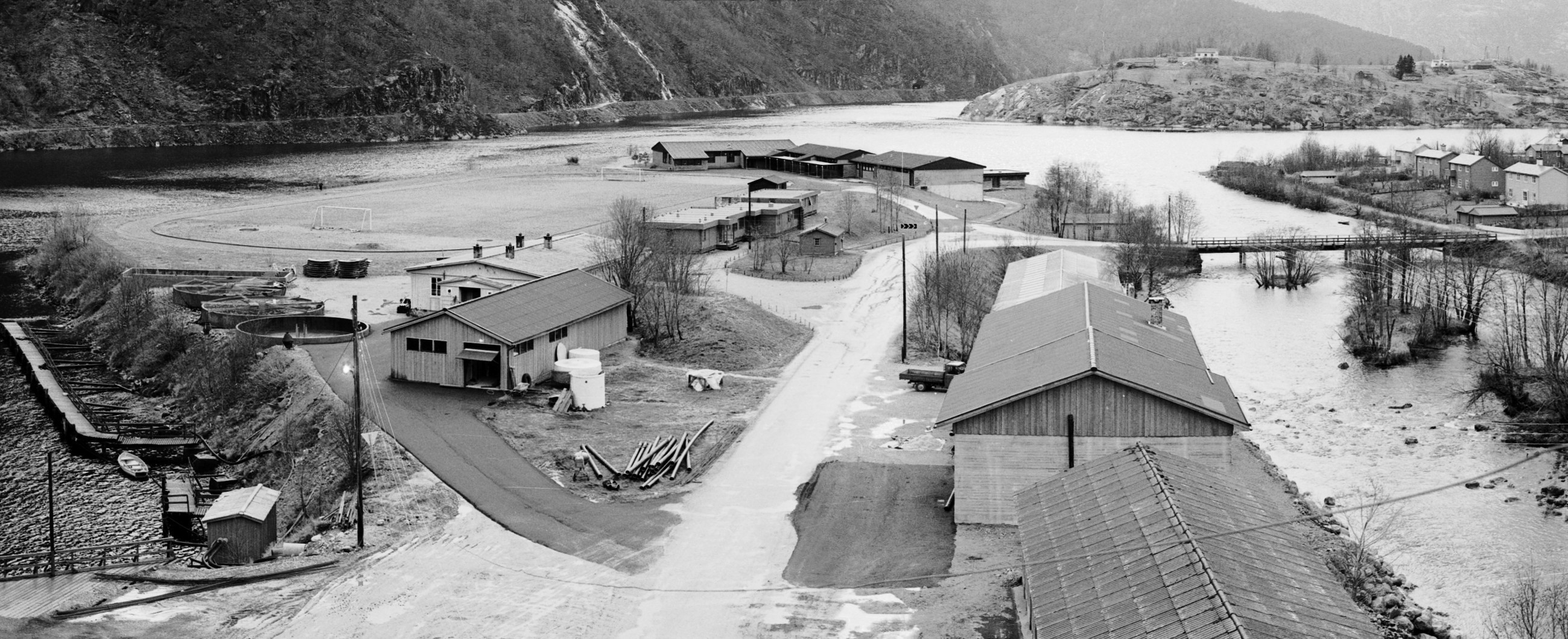 Black and white picture og the research station with new buildings and the fjord in the background.