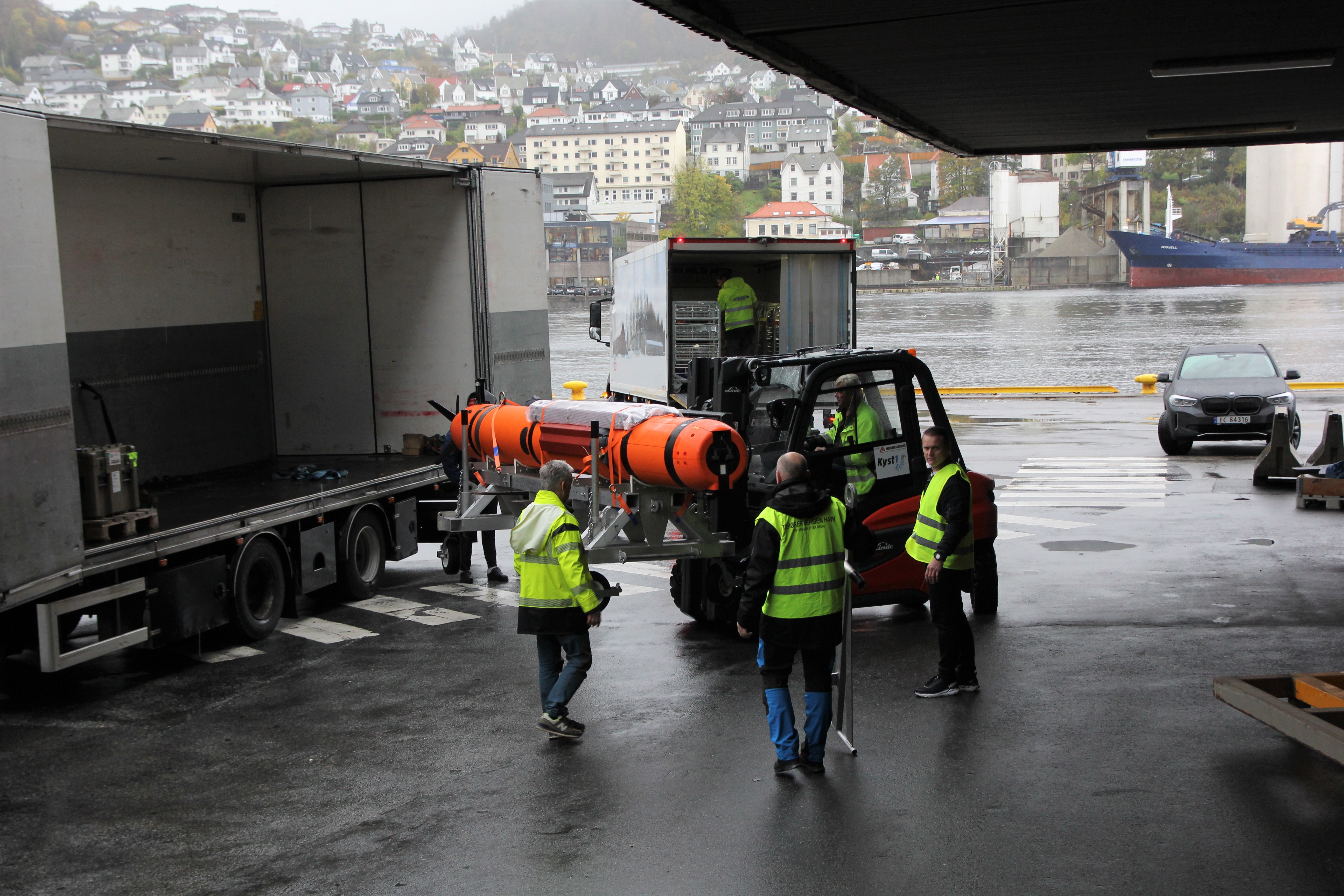 Sigarforma farkost blir lasta ut av ein konteiner.