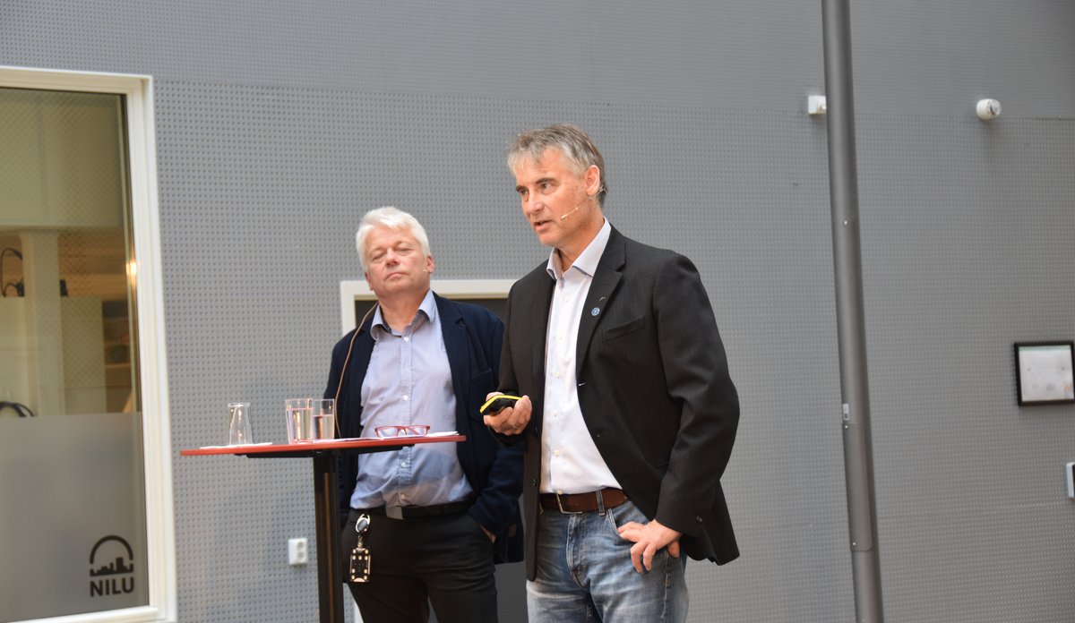 To menn på scene med storskjerm bak seg 