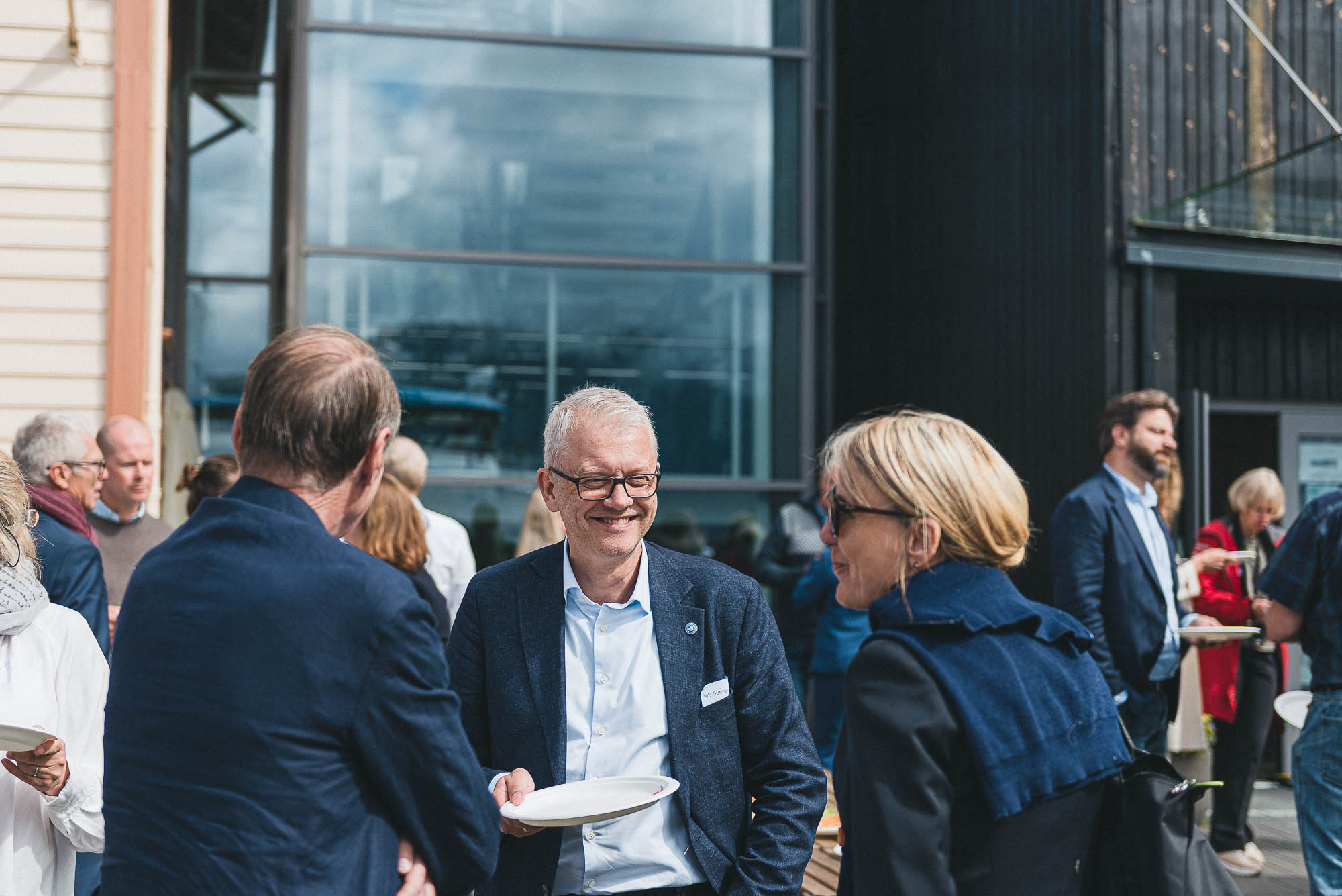 Havforskningsdirektør Nils Gunnar Kvamstø pratar med deltakarar på Rosendalsveko 2022. Han held eit tomt kakefat i handa og smiler breitt.  
