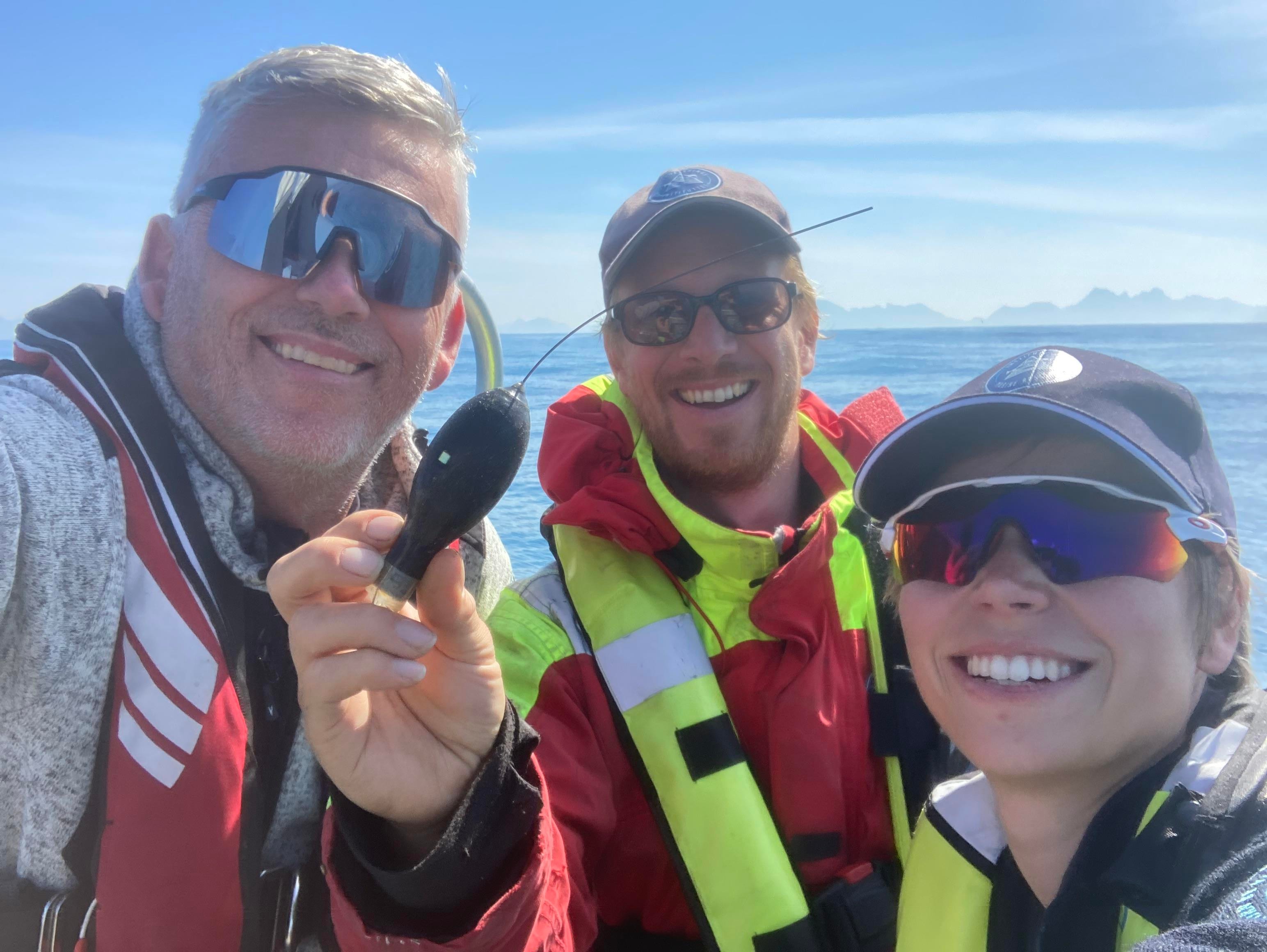 Bildet viser havforskerne Keno Ferter, Otte Bjelland og stipendiat Antonia Klöcker. De smiler med solbrillene på og viser frem et satelittmerke som ble funnet og hentet opp i 2023.