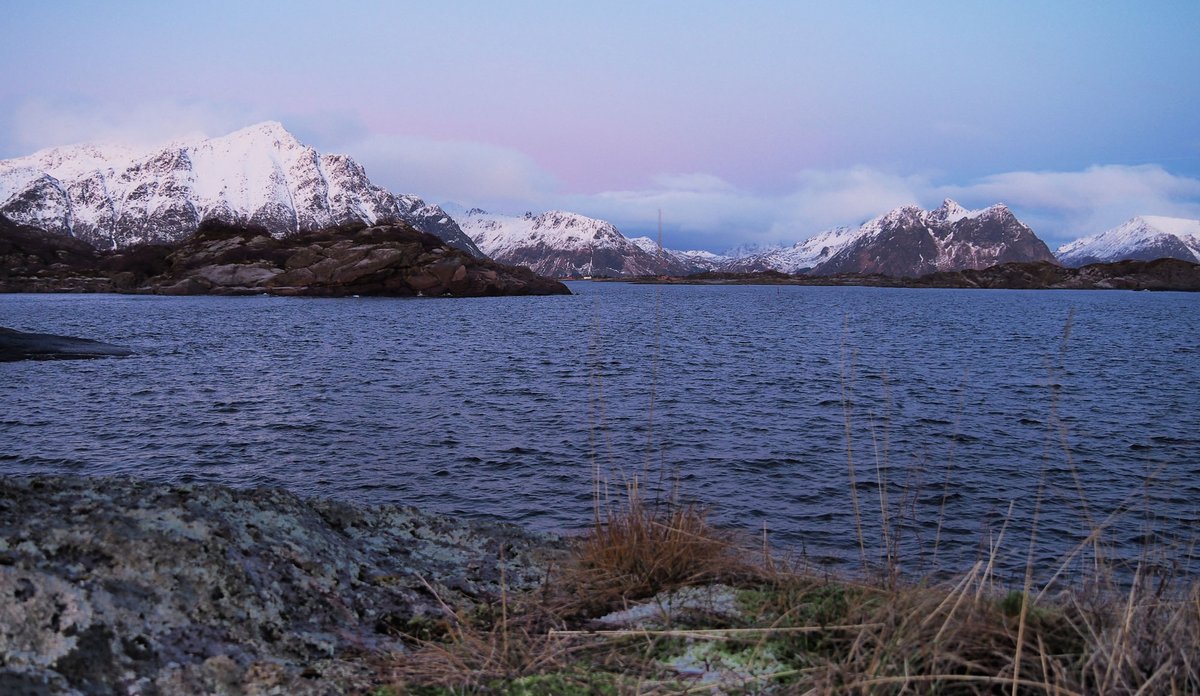 
Foto av fjor og snødekte fjell, himmel med kveldslys farga i blåtoner.