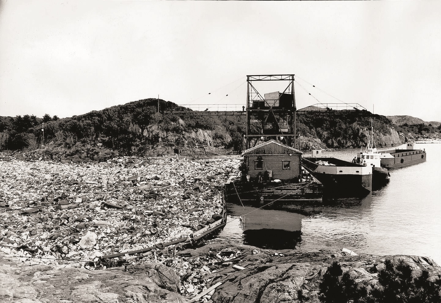 svart/hvitt-foto av gammel bossfylling ved fjorden