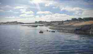 foto av en mann som svømmer i overflaten med våtdrakt i vakker skjærgård og sol