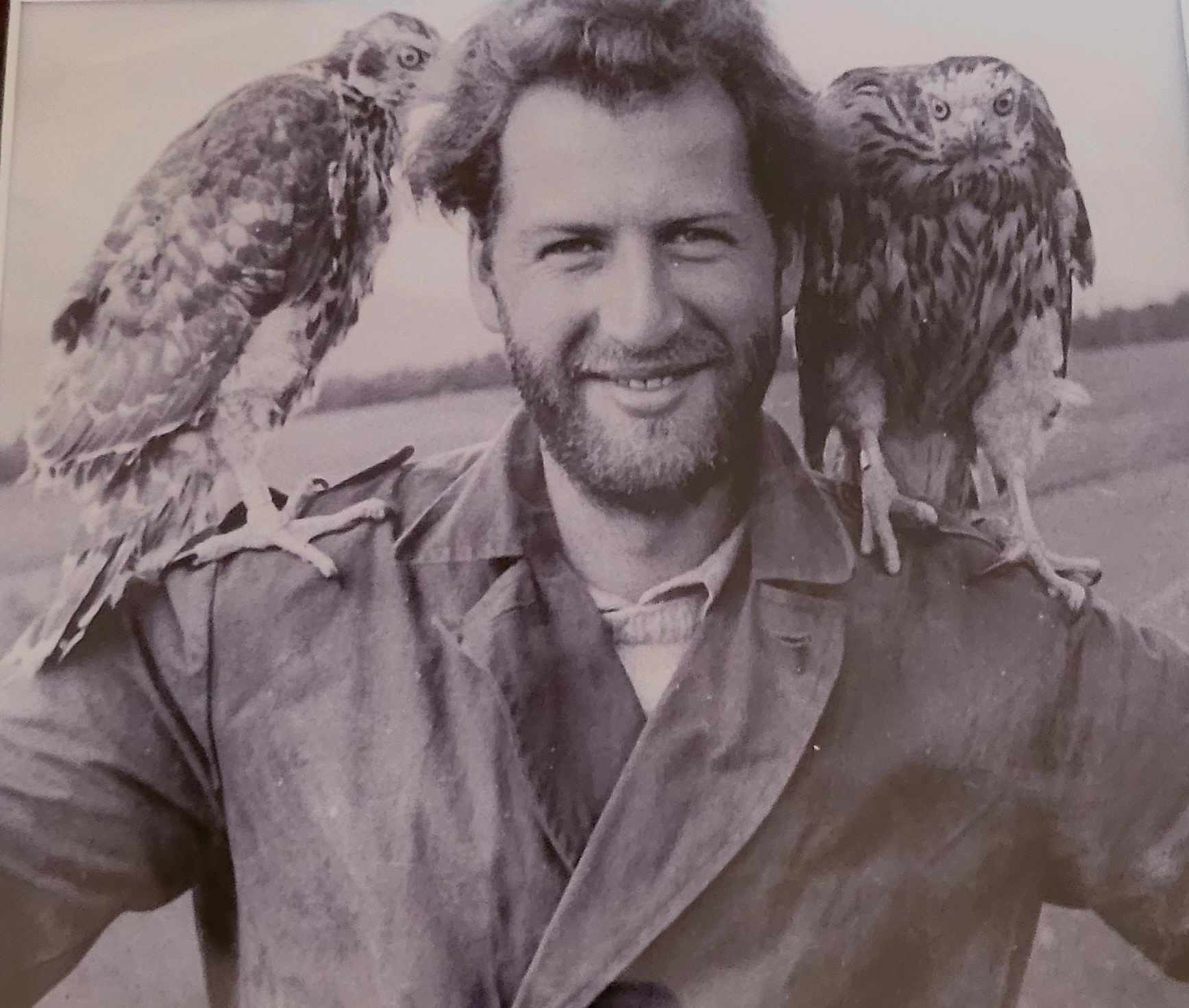 mann smiler i kamera. Har en ørn på hver skulder. 