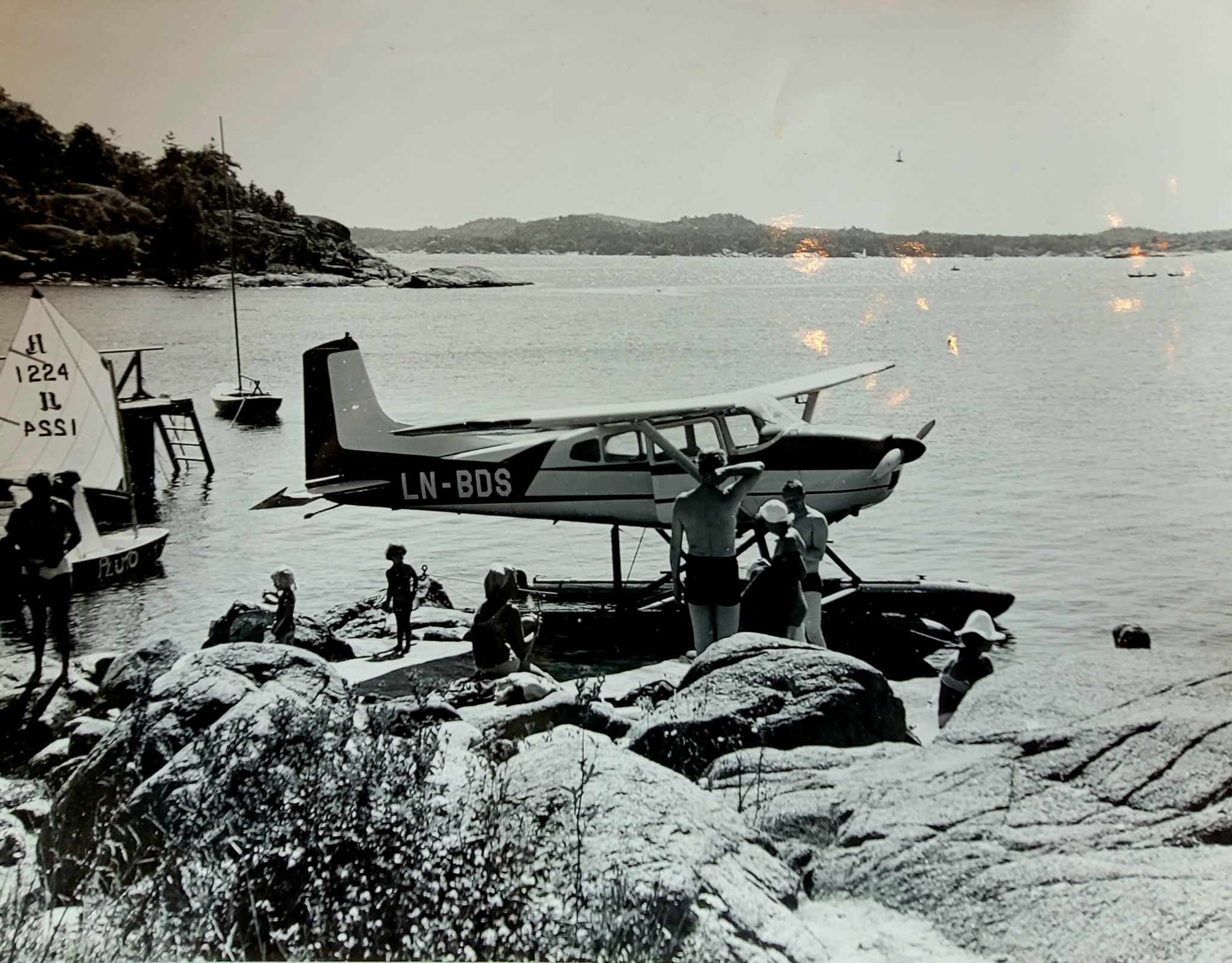 gammelt bilde av folk i badetøy som står ved et sjøfly på vannet