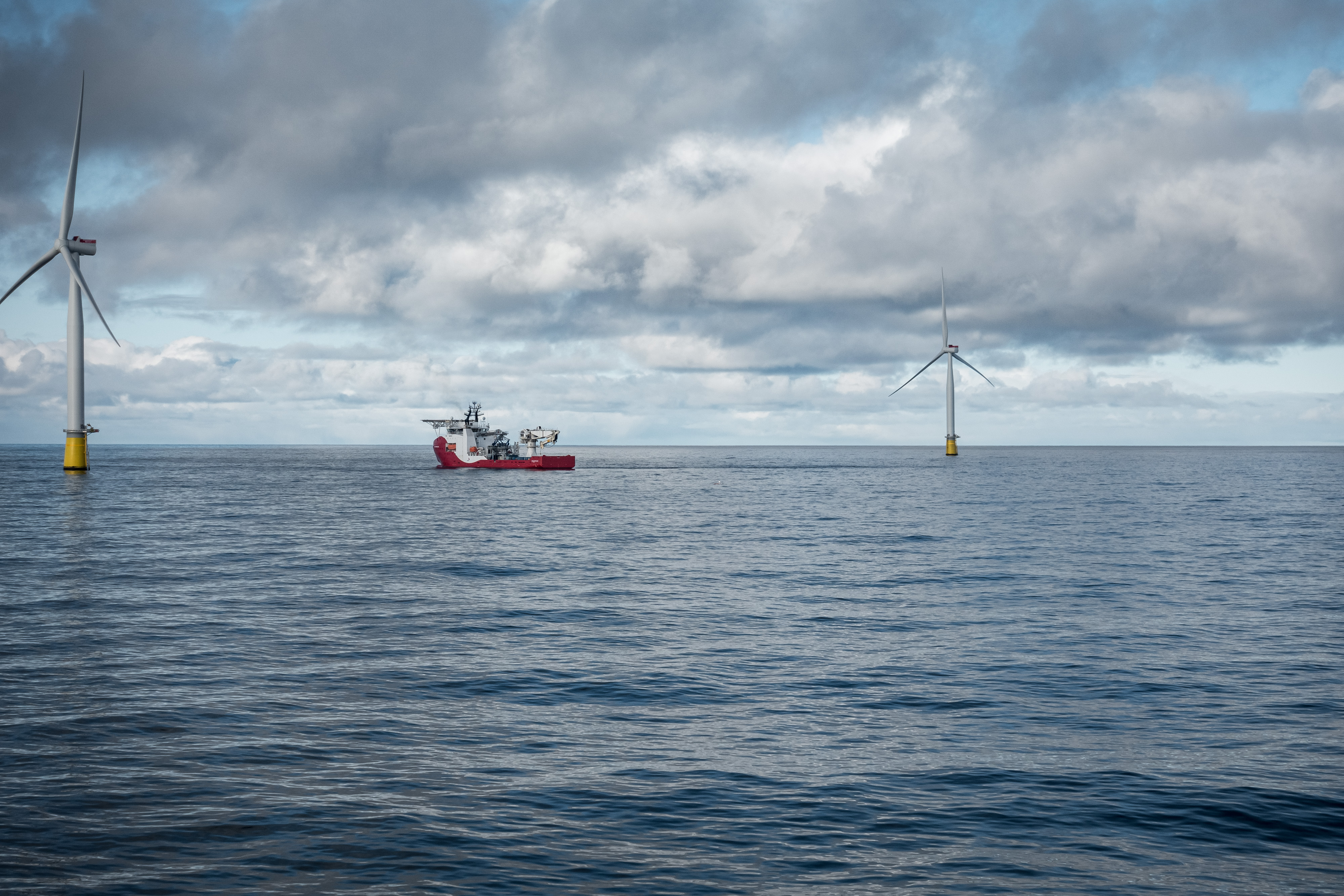 to store turbiner og et skip i åpent blått hav, skyer på himmelen