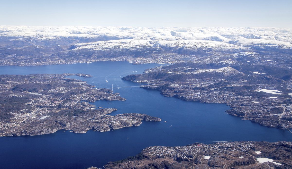 
Fjordlandskap med snøkledde fjell i bakgrunnen, sett fra et fly 
