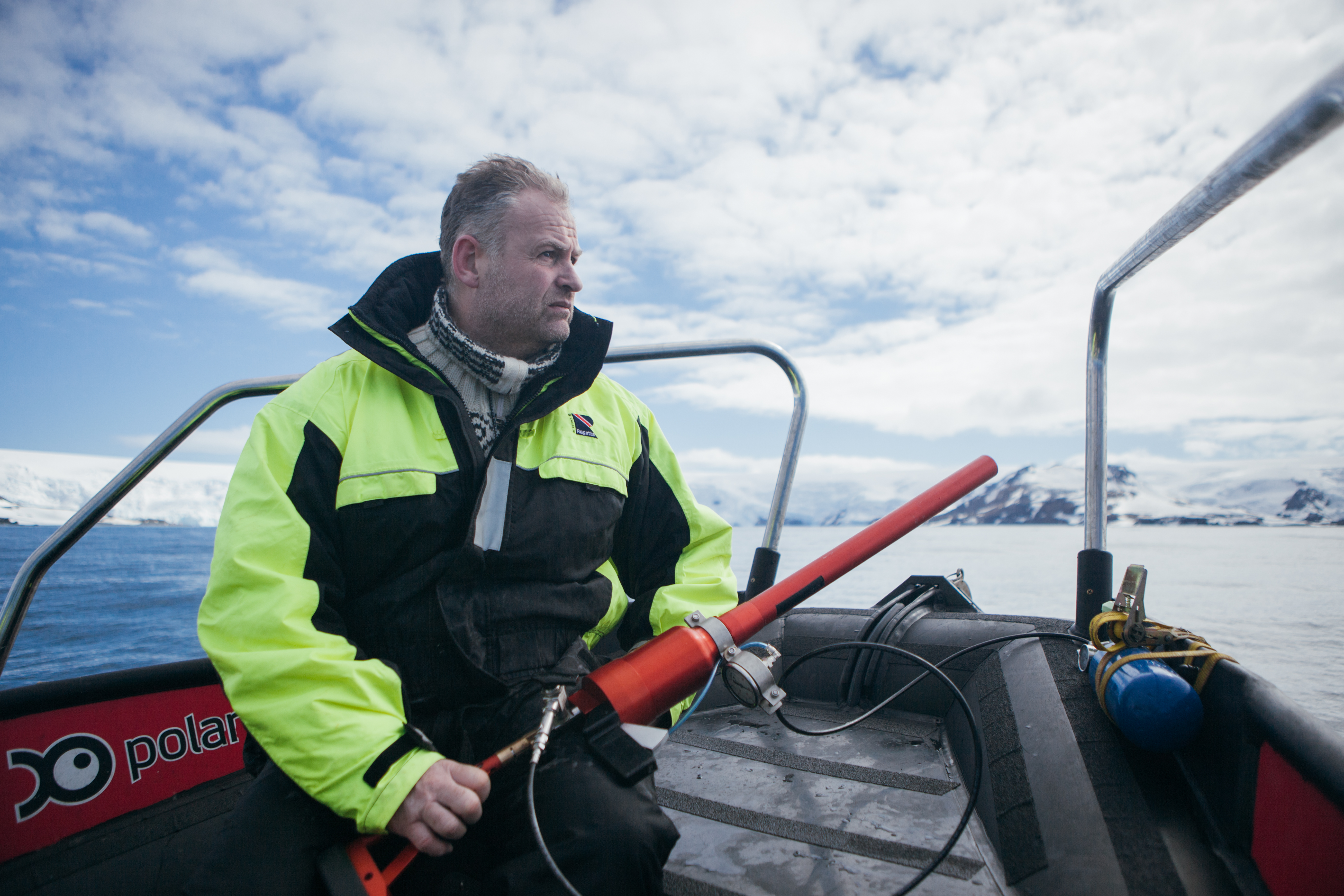 mann med harpun i hendene, sittende i båt