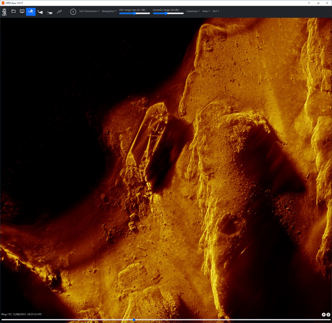Figuren viser et undervannsbilde av havbunnen, hvor man ser rester av et skip med ødelagt akterende 