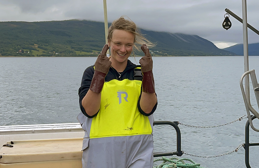Johanna står på dekk og krysser fingrene på begge hender. Hun har hansker på.