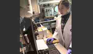 Kvinne står foran en PC inne på lab om bord på et forskningfartøy.